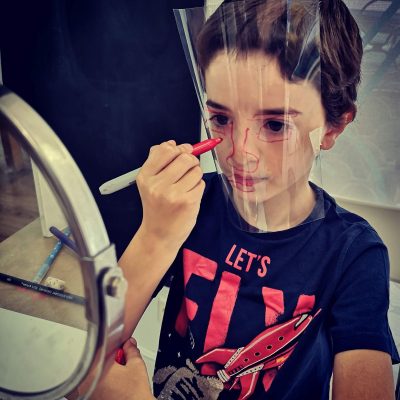 niño delante de un espejo pintándose la cara sobre acetato